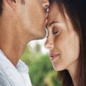 young man kissing his cute girlfriend on forehead